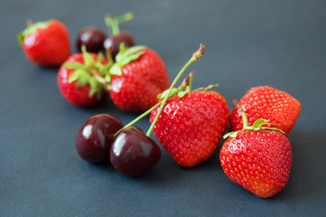 strawberries and cherry on black background