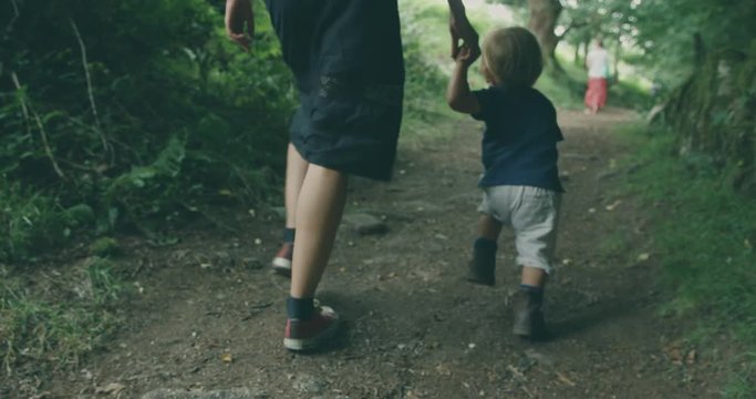 Young mother and little toddler walking in the forest