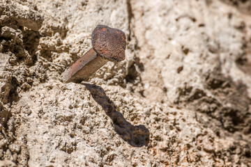 Large nail sticking out on a stone wall.