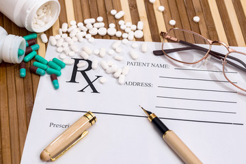 Empty prescription with dispersed pills, glasses and pen
