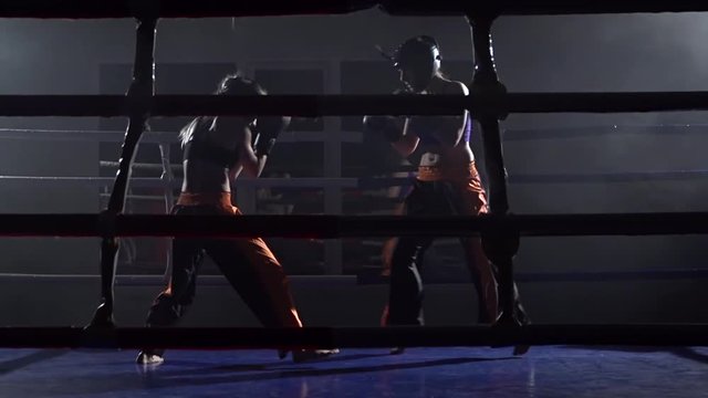 Sparring in the ring between two girls in a dark space. Slow motion
