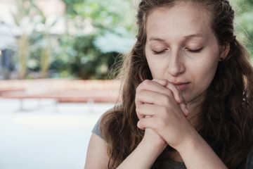 Fototapeta na wymiar Young woman praying with eyes closed