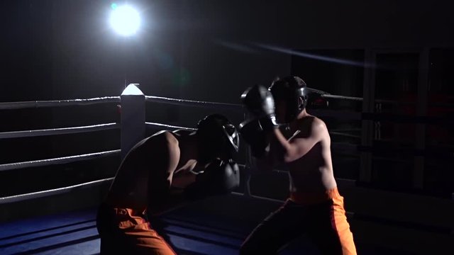 Two guys are preparing for kickboxing competitions. Slow motion. Silhouette