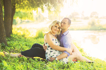 beautiful couple spends time romantically on the river bank at sunset in warm summer weather. the embrace of a man and a woman. I love