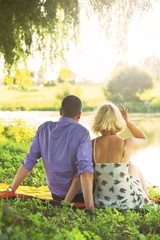 beautiful couple spends time romantically on the river bank at sunset in warm summer weather. the embrace of a man and a woman. I love