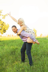 Cheerful loving woman and man spoiling on nature at sunset