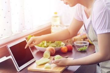 Obraz na płótnie Canvas Asian woman use finger slide on tablet screen prepare ingredients for cooking follow cooking online video clip on website. cooking content on internet technology for modern lifestyle concept