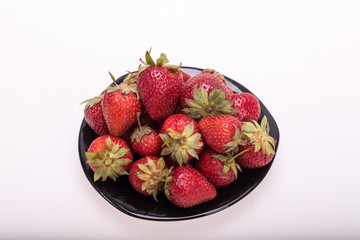 fresh ripe strawberries on black plate isolated on white background