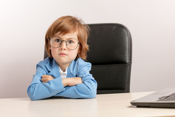 handsome little boy in round glasses is pretending a CEO of the company. kid with artistic skills....