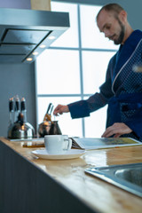 Fototapeta premium A cup of coffee on the background of a man who cooks coffee on the stove
