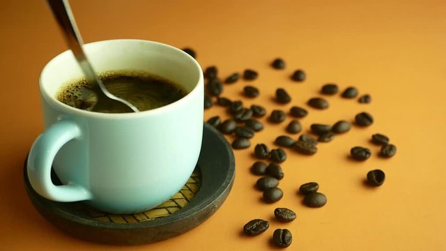 Hand Stirring Coffee With Bubbles In A Cup Top View