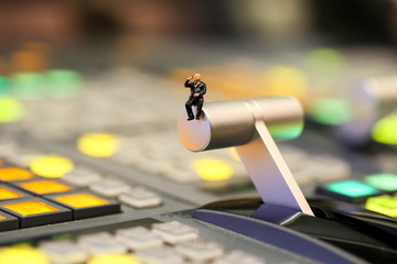 Miniature people : businessman sitting on switcher control of Television Broadcast,color buttons