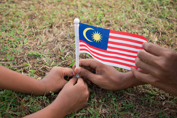 Independence Day concept. Kids' hands holding Malaysian flag.