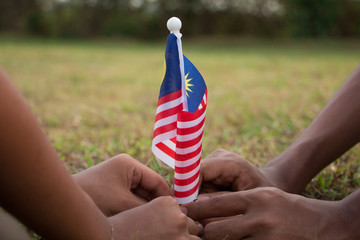 Independence Day concept. Kids' hands holding Malaysian flag.