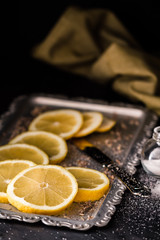 Obraz na płótnie Canvas Fresh Sliced Ripe Lemons on Plate, with Salt and Knife on Black