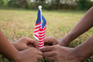 Independence Day concept. Kids' hands holding Malaysian flag.