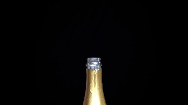 Bottle of champagne and falling cork on black background