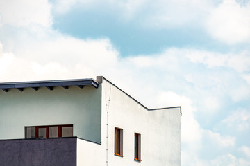 Section of a penthouse from an apartment building in front of beautiful sky with fluffy clouds with room for text