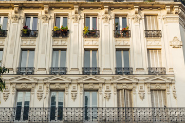 Old Paris residential buildings with balconies and flowers. Beautiful facade of typical french city house. Background. European architecture and city life, lifestyle and expensive real estate concept