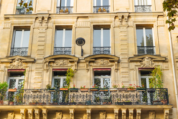 Obraz premium Old Paris residential buildings with balconies and flowers. Beautiful facade of typical french city house. Background. European architecture and city life, lifestyle and expensive real estate concept