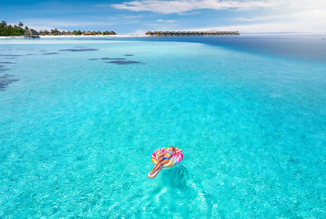Attraktive Frau treibt auf aufblasbaren Lolli über das türkise Wasser der Malediven und genießt...