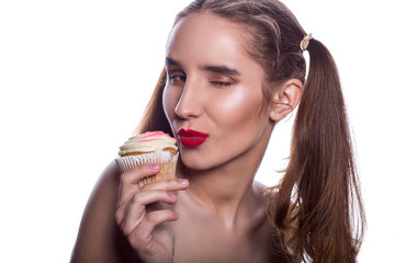 Blinking brunette woman enjoying flavorous cupcake with cream. Space for text