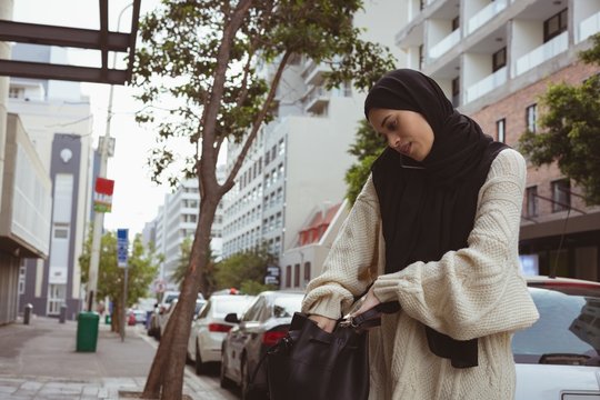 Hijab Woman Talking On Mobile Phone While Checking Her Purse