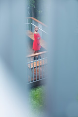 Awesome blonde woman wearing fashionable red dress, posing on the wooden bridge with railing