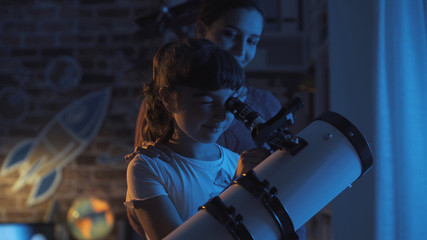 Cute sisters watching the stars with a telescope