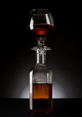 cognac glass on a bottle on dark bg studio shot