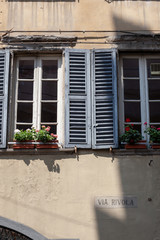 Fototapeta na wymiar Window shutters with flowers in Bergamo, Italy