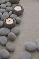 Fototapeta na wymiar Pile of gray stones with candle and grey background
