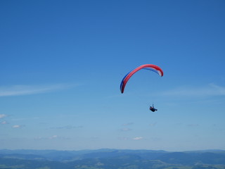 Carpathians / Ukraine - July 07 2017: Paraglider flying parachute in blue sky at a bright sunny summer day. Active lifestyle