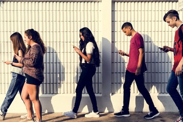 Group of young teenager friends walking home after school using smartphones addiction concept - obrazy, fototapety, plakaty