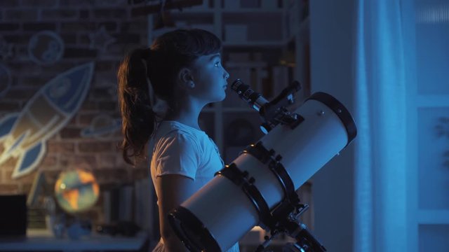 Cute girl watching the stars with a professional telescope