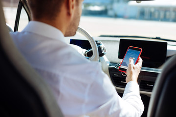 Modern innovations. Professional male driver using his smartphone while checking the weather...