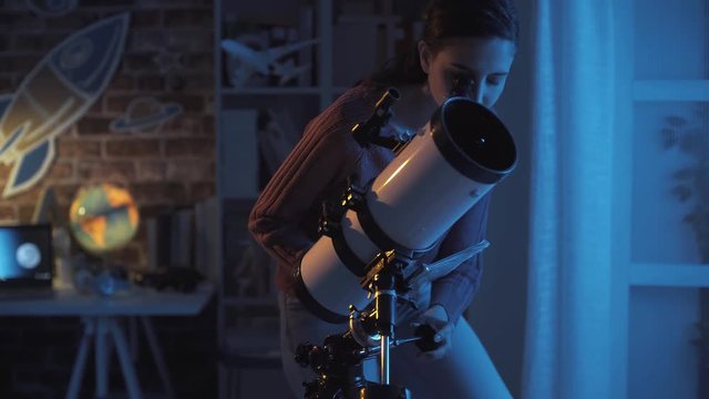 Young woman watching stars with her telescope at night