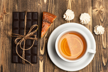 Tea cup with cake, bar of chocolate and meringue