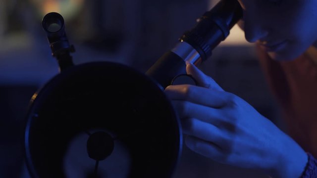 Young woman stargazing with a professional telescope