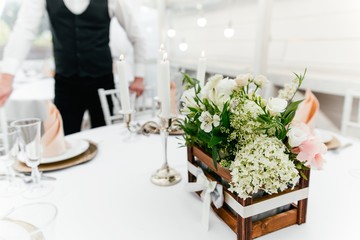 Fresh flowers standing on the table served in the restaurant on the background of the waiter