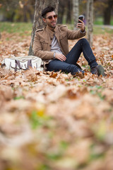Young adult man handsome taking selfie in the wood, winter autumn day