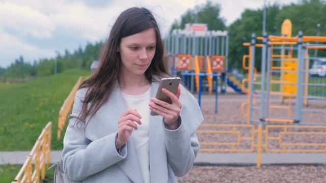 Young woman shoots a video on a mobile phone on the Playground.