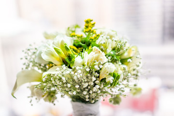 Closeup of flower bouquet in front of bright sunny window in room of hotel, many flowers arrangement