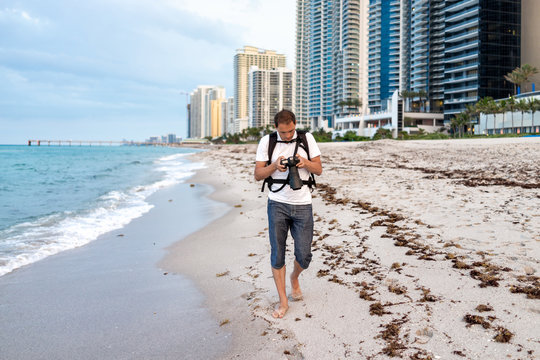 Sunny Isles Beach buildings during evening in Miami, Florida with sand, pier, shore coastline, people person photographer man walking with camera