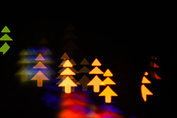 Obraz premium Lights of christmas garland blurred on black background. Lights of colorful garland blurred as beautiful background. Christmas holiday decoration with silhouette of christmas trees. Christmas concept