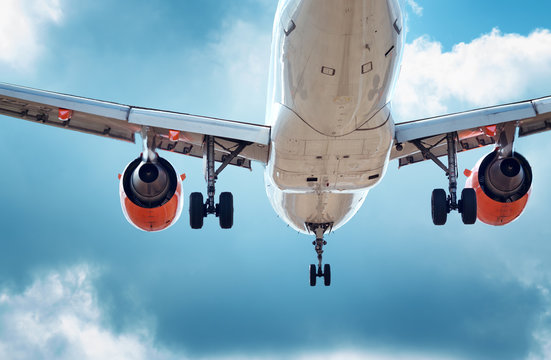 Fototapeta plane at landing on blue sky background with white clouds. Airplane turbine and wing view