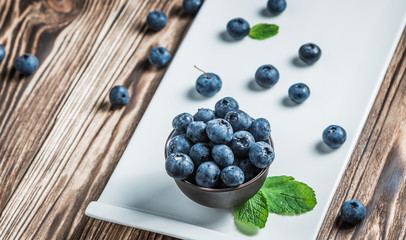 blueberry with mint on a white plate on a wooden background