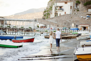 Fototapeta na wymiar A young couple walks along the beach, in the port of Sorrento, Italy.
