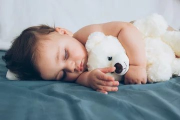 Fototapeten Beautiful baby sleeping with his teddy bear aside, family concept © nehopelon