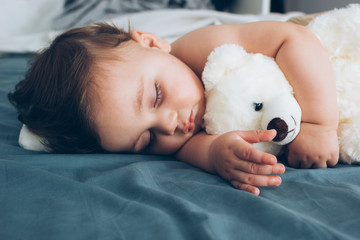 Beautiful baby sleeping with his teddy bear aside, family concept
